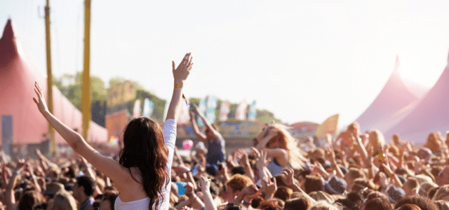 Frau sitzt auf dem Rücken einer Person. Es sind viele feiernde auf dem Bild zu sehen.